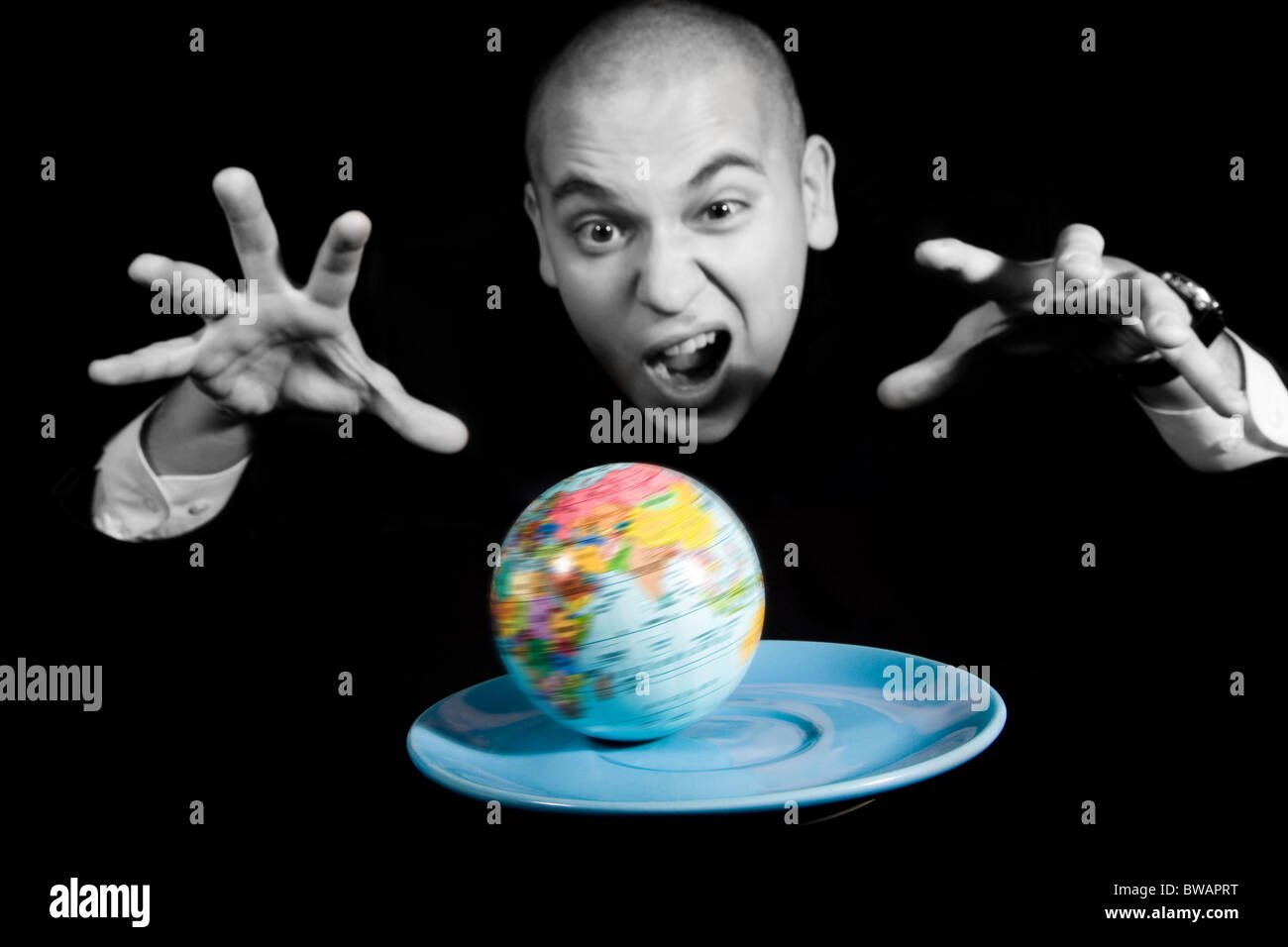 Furious man screaming while trying to capture earth rotating on blue saucer Stock Photo