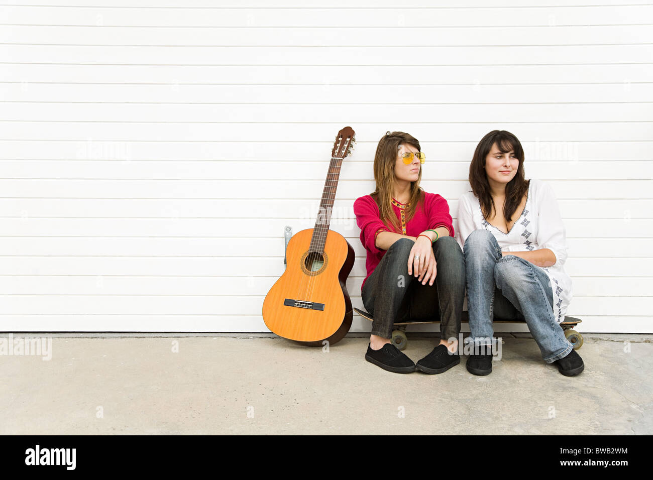 Two girls sitting on floor with guitar Stock Photo