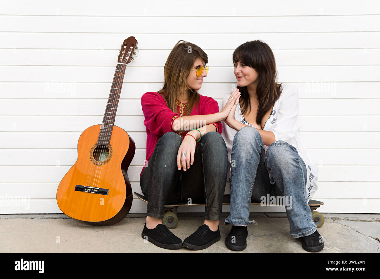 Two girls sitting on floor with guitar Stock Photo
