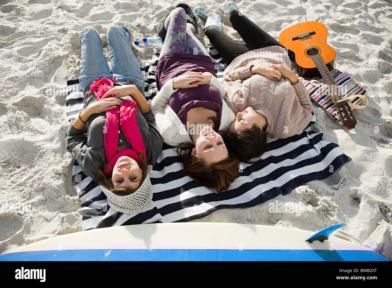 Three girls lying on beach with guitar Stock Photo Alamy
