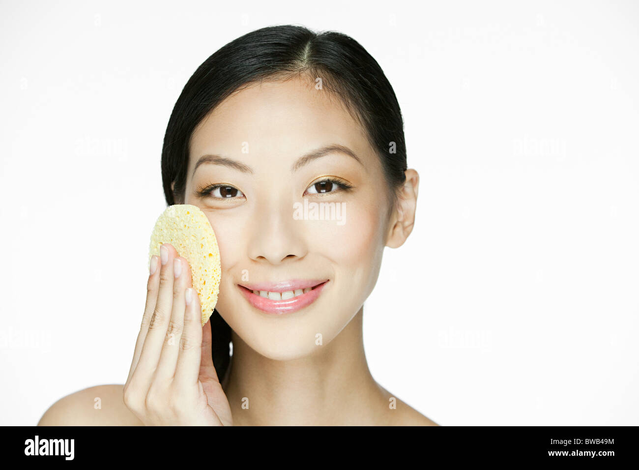 Young woman using sponge on face Stock Photo Alamy