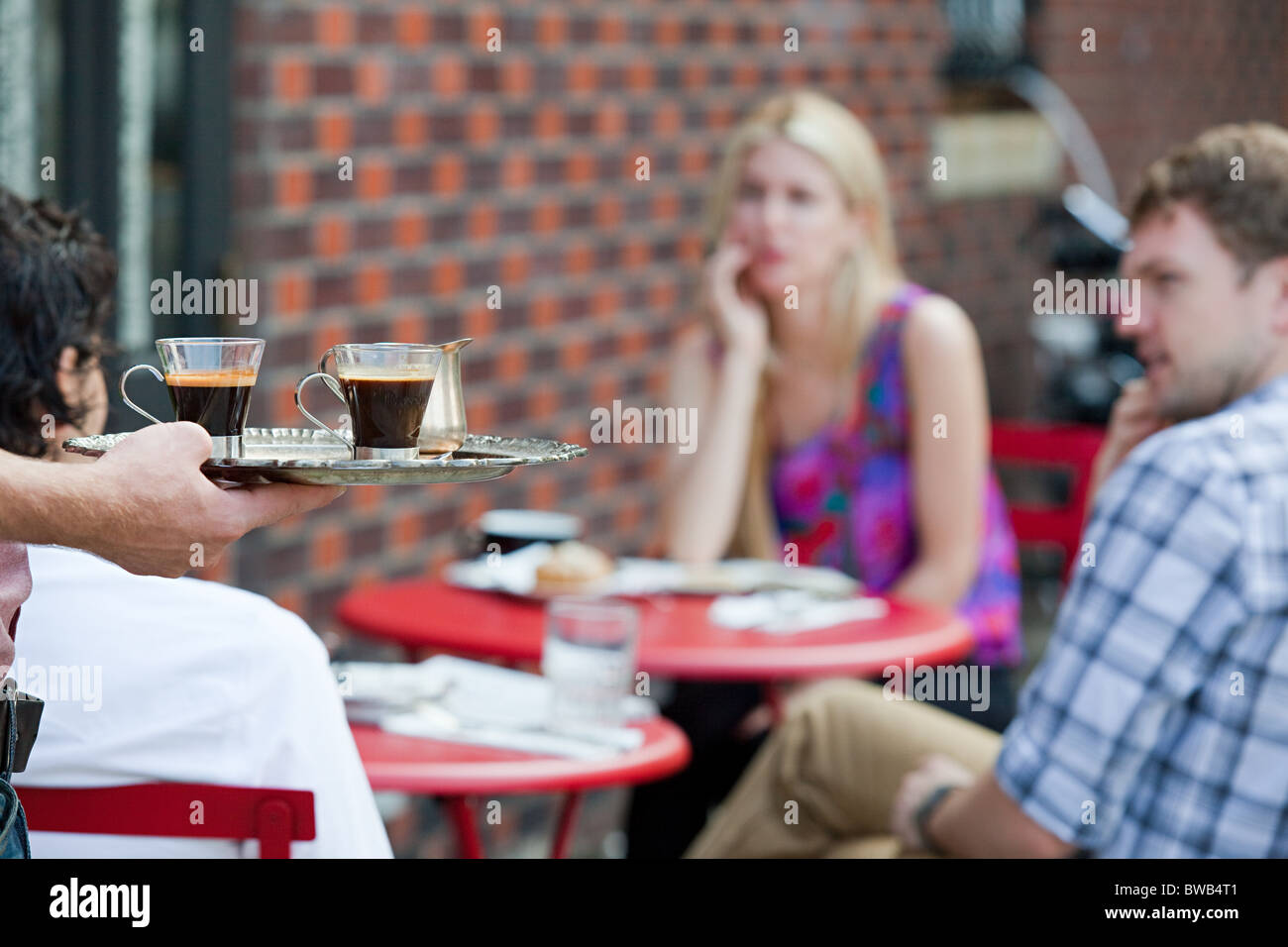 Waiter with coffee for people outside cafe Stock Photo