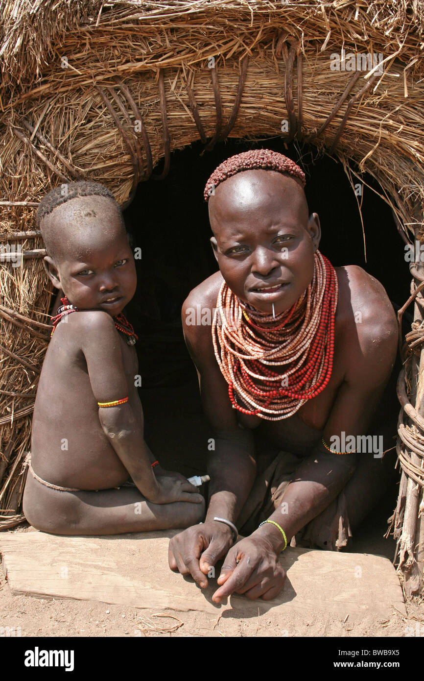 Karo Tribe Woman With Baby In The Entrance To Her Hut, Omo Valley, Ethiopia Stock Photo