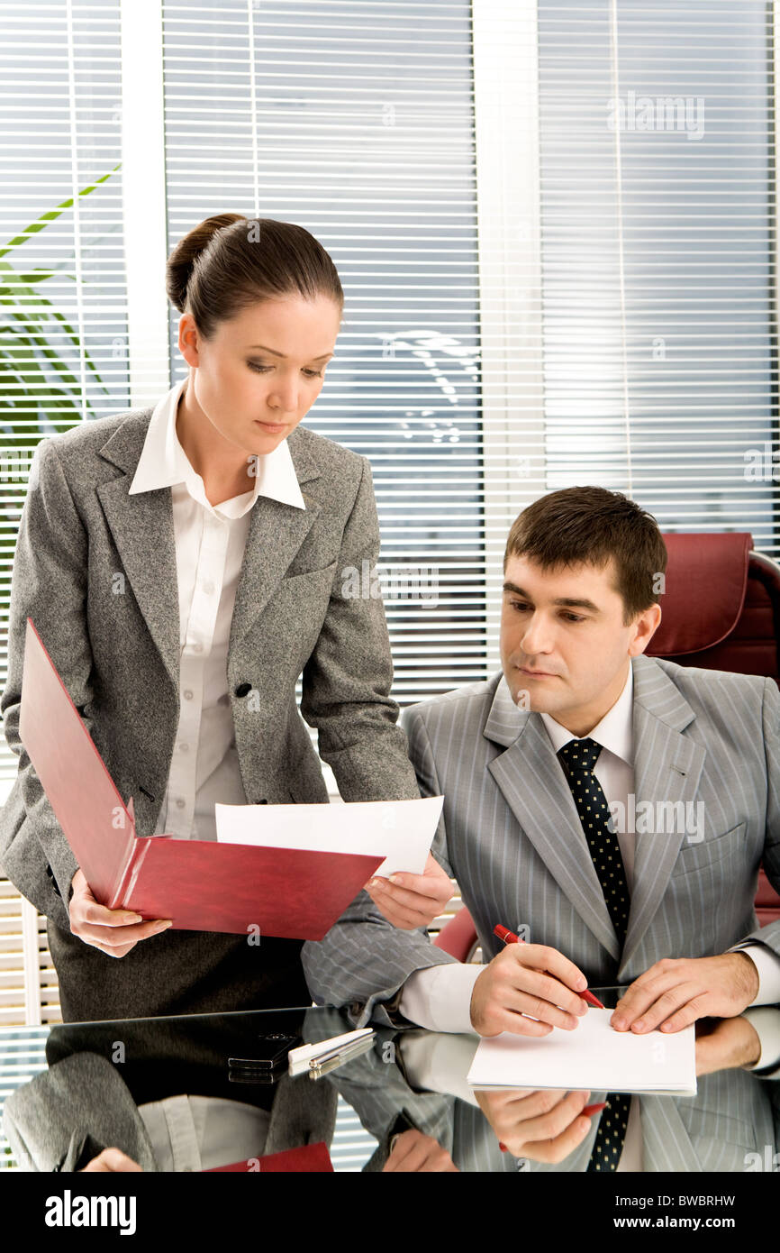 Pretty secretary showing papers to her boss in office Stock Photo - Alamy