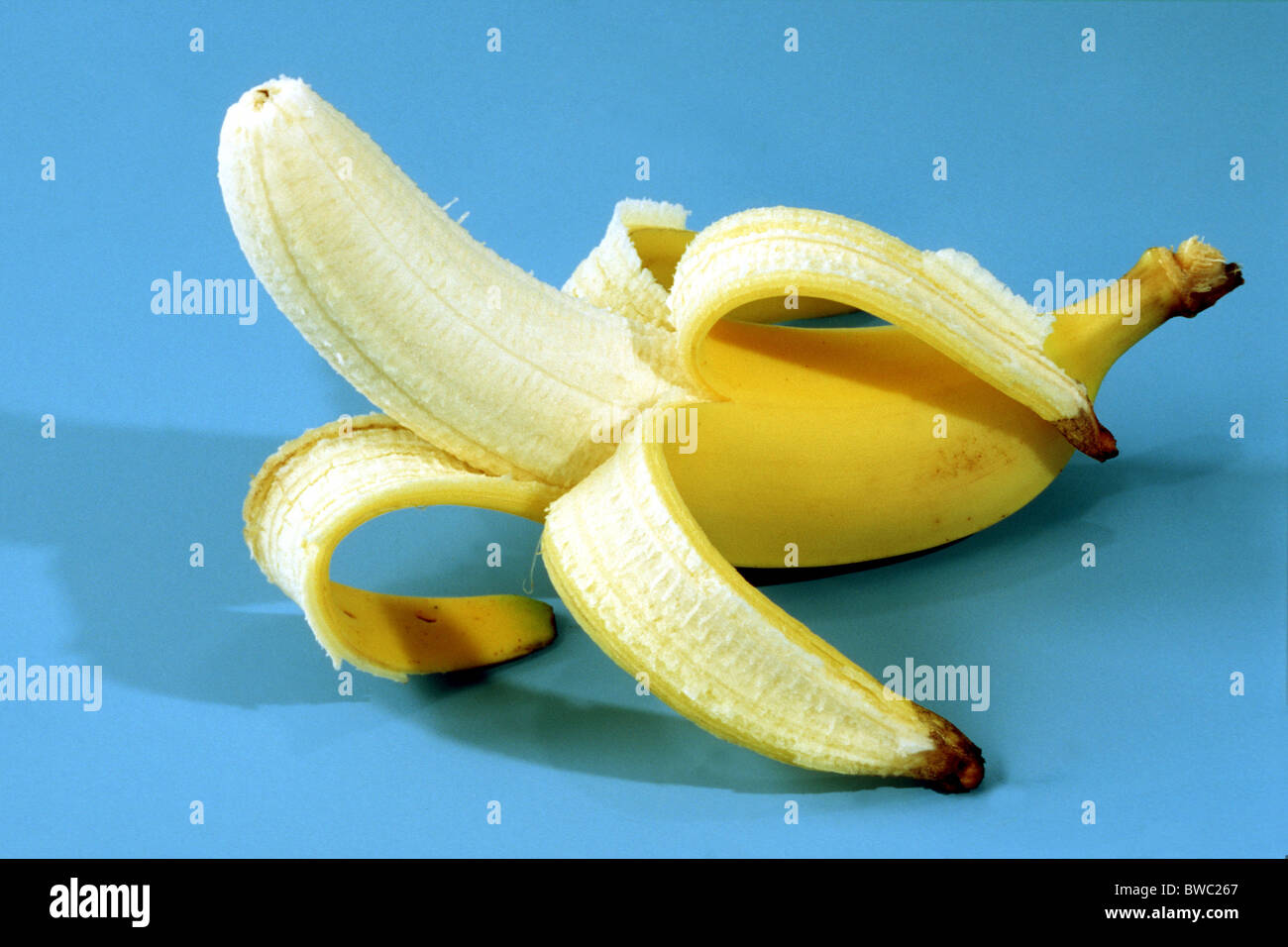 Banana (Musa x paradisiaca), half peeled fruit, fruit. Studio picture. Stock Photo