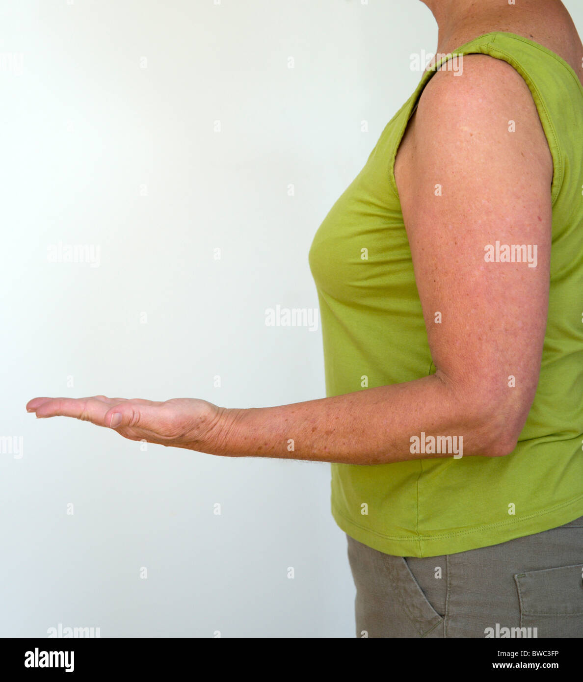 Health, Body, Arms, Woman in profile from side with arm bent at elbow with palm of hand facing upwards and fingers outstretched. Stock Photo