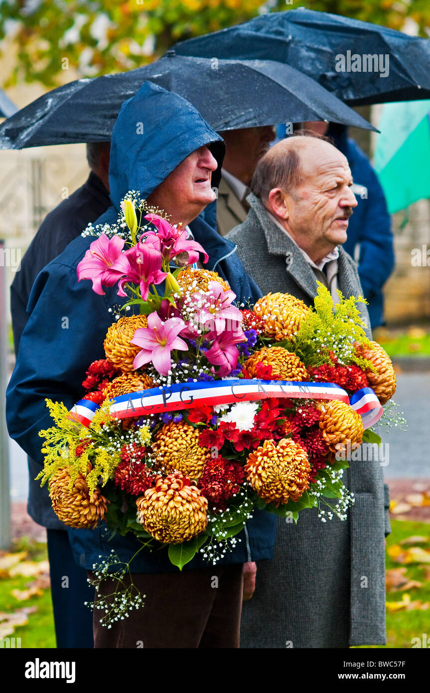 Old soldiers / civilians carrying wreaths of flowers at Remembrance Day parade - France. Stock Photo