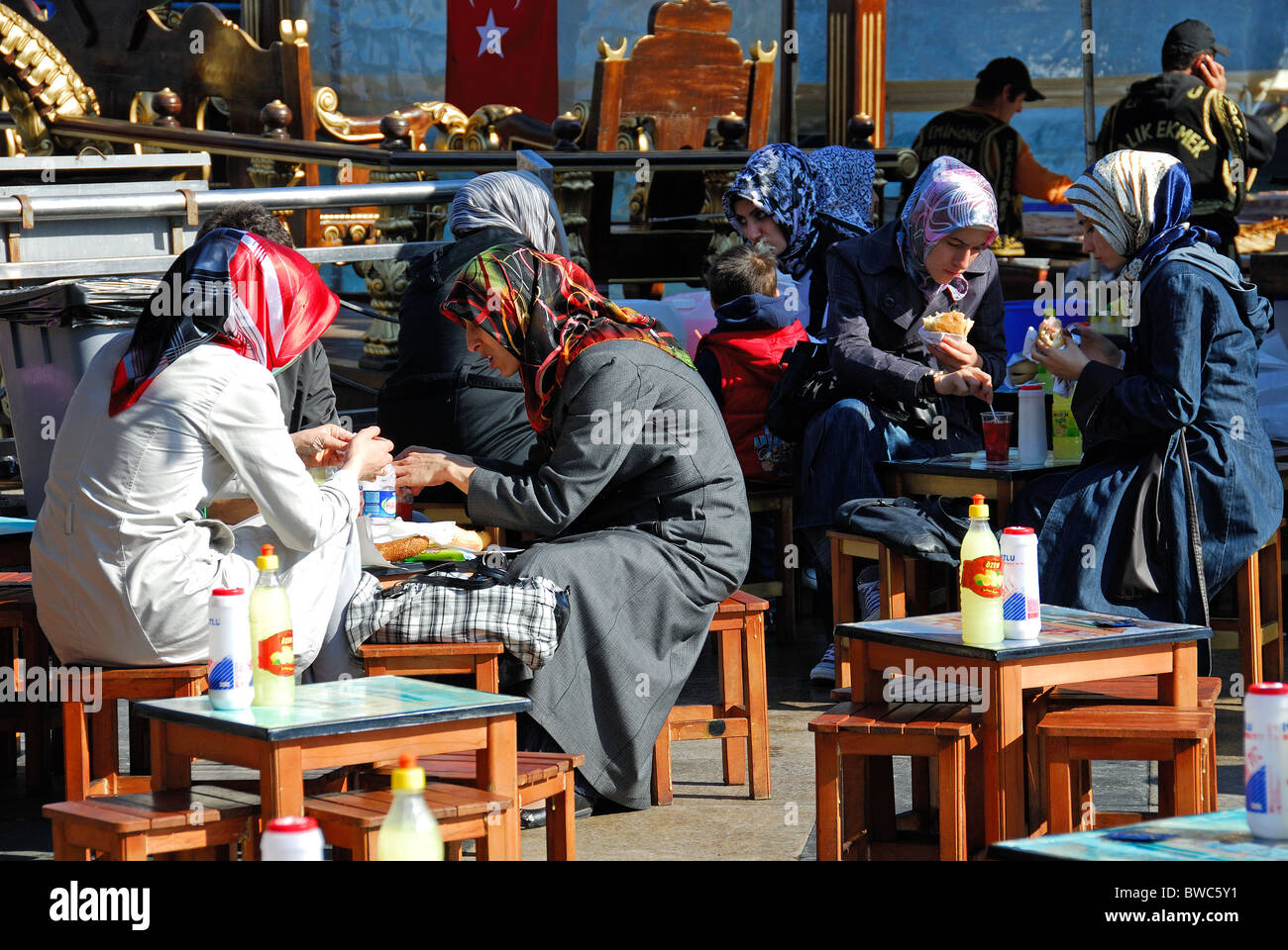 ISTANBUL, TURKEY. Young Turkish women eating balik ekmek (mackerel sandwiches) beside the Golden Horn in Eminonu district. 2010. Stock Photo