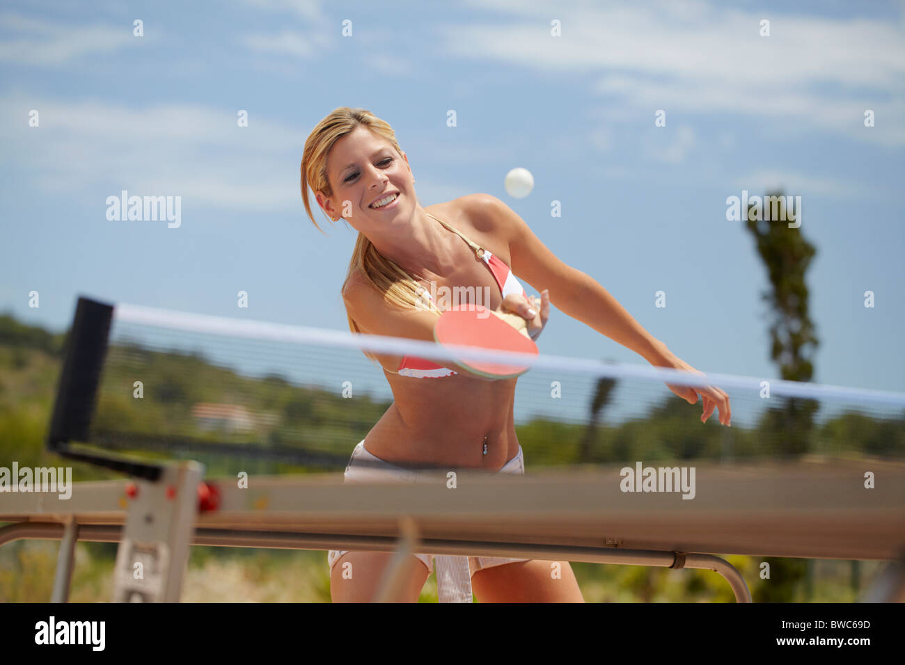 Woman in bikini playing table tennis Stock Photo
