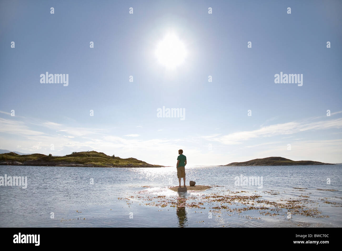 Man standing on rock in sea Stock Photo