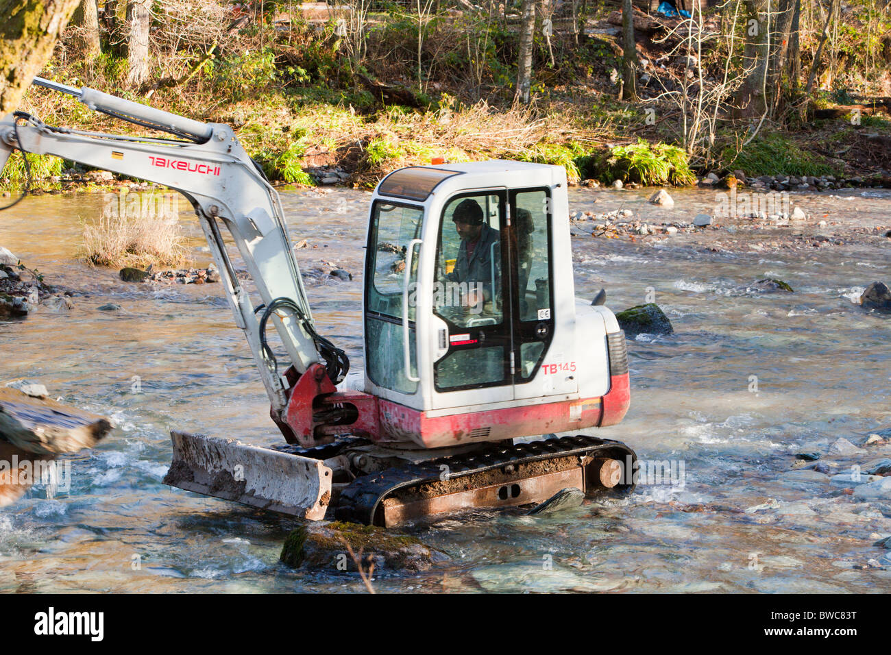 A mini digger helping to rebuild a weir that got destroyed in the November 2009 floods across the river Brathay Stock Photo