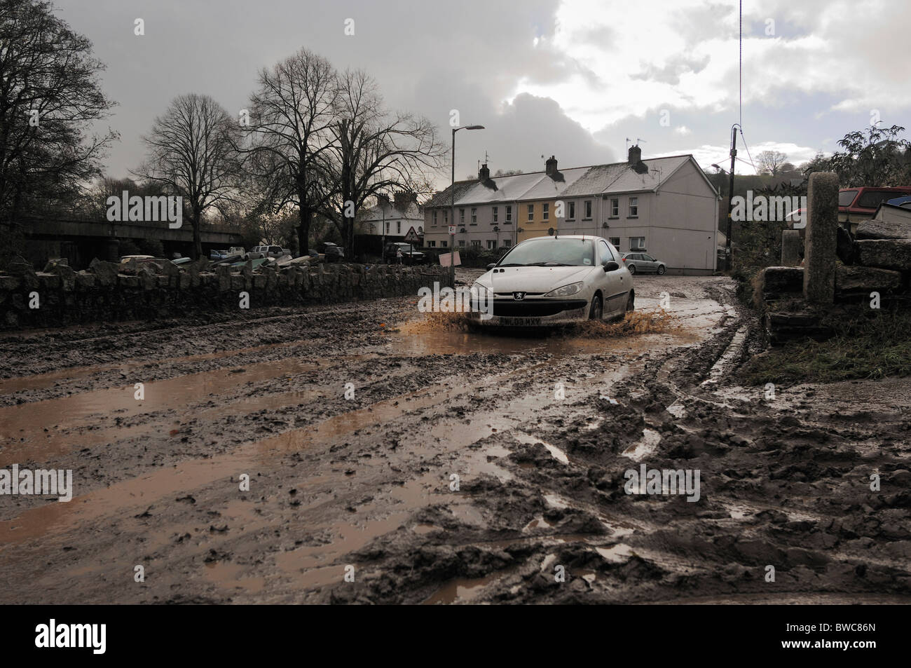 Car Driving through mud covered road in Lostwithiel after flash flooding 18/11/2010 Stock Photo