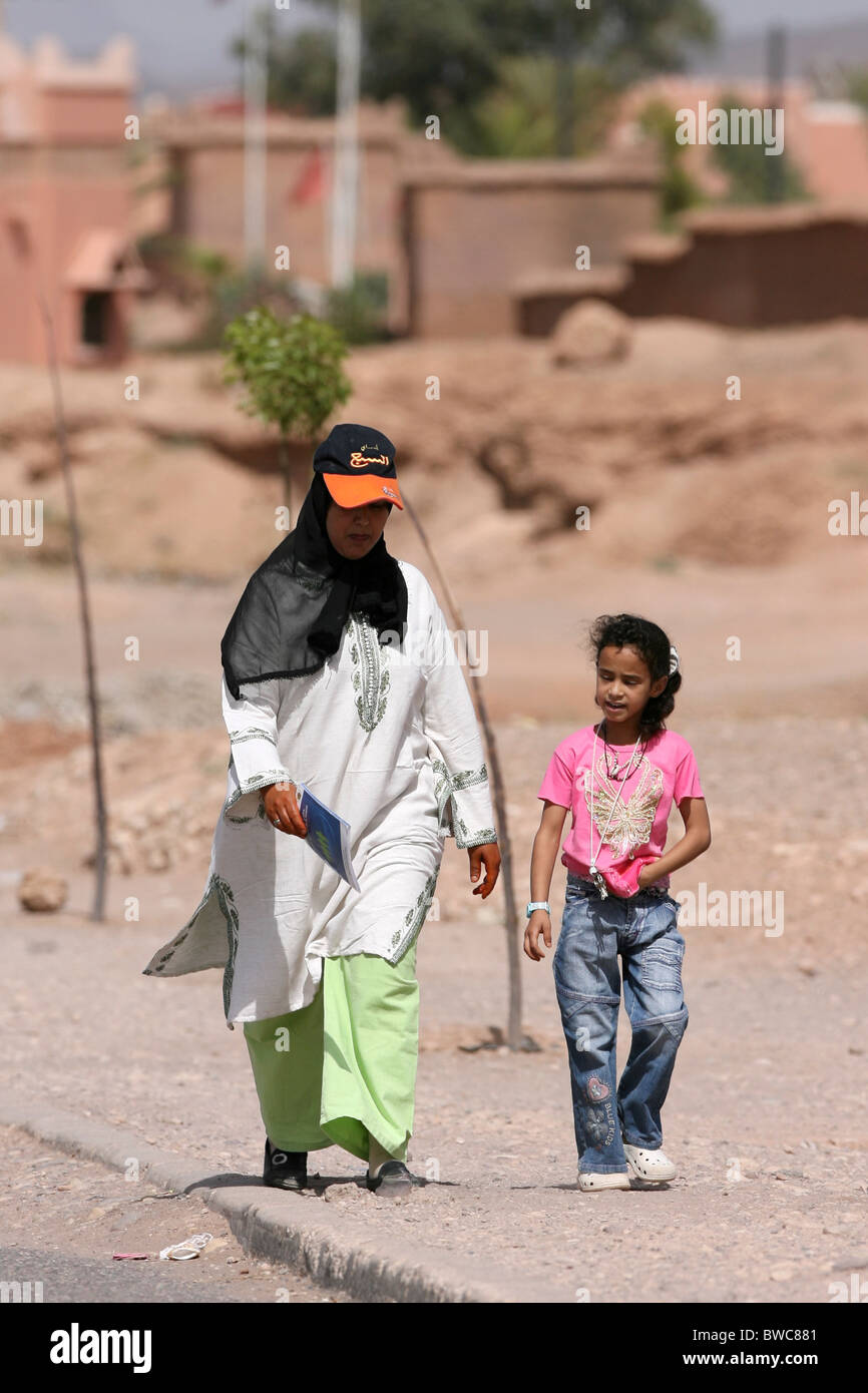 A Moroccan woman and a girl walk down a road Stock Photo