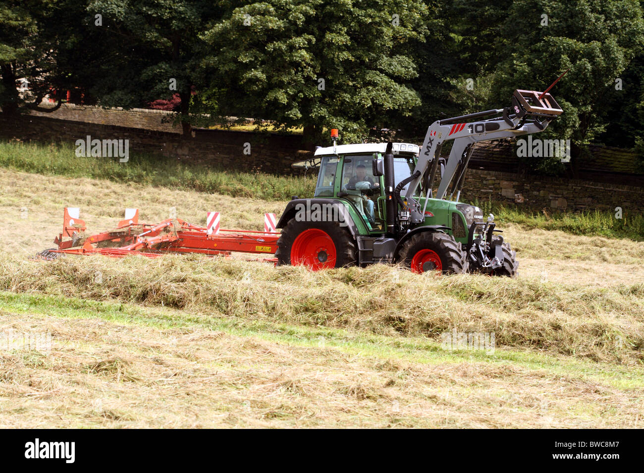 Harvest Time in a Hay Meadow near Shelf Yorkshire showing a tractor furrowing hay Stock Photo
