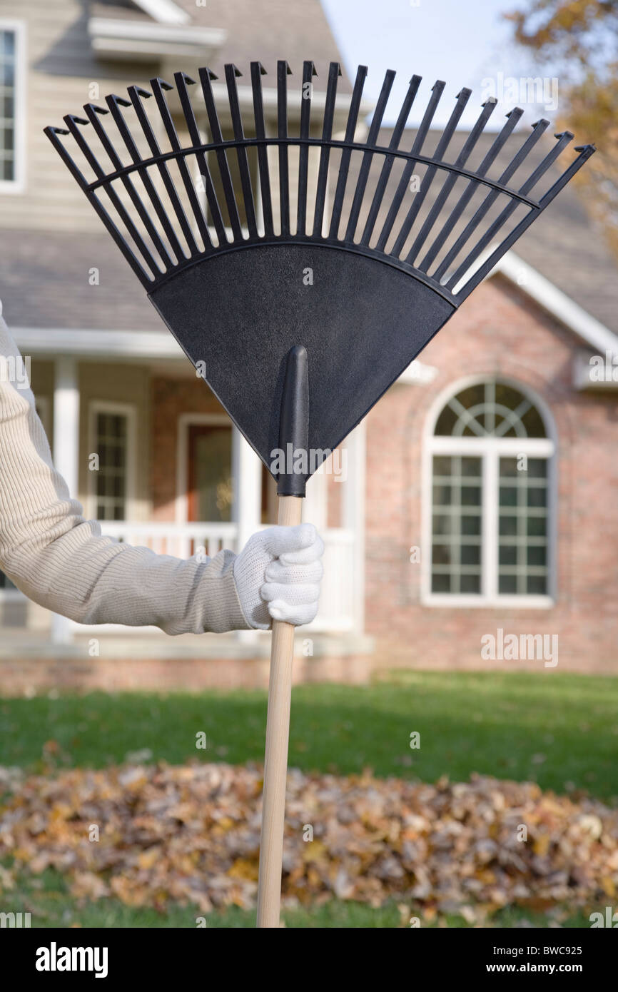 Person holding rake in lawn, close-up of hand Stock Photo