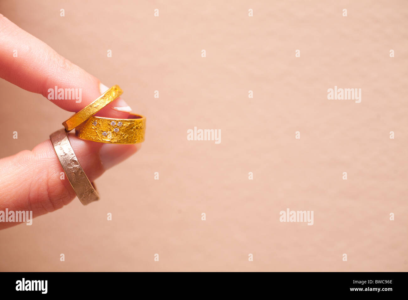 Wedding rings and engagement ring between the fingers of the bride