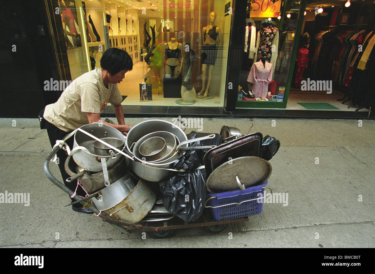 Worker with trolley of pots and pans, in Hong Kong, China Stock Photo
