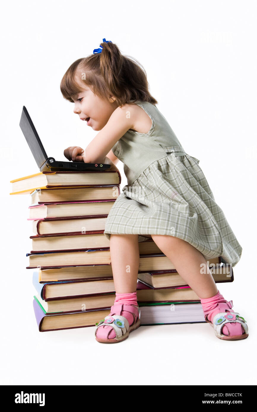 Amazed girl of preschool age sitting in front of laptop and looking into its display with open mouth Stock Photo