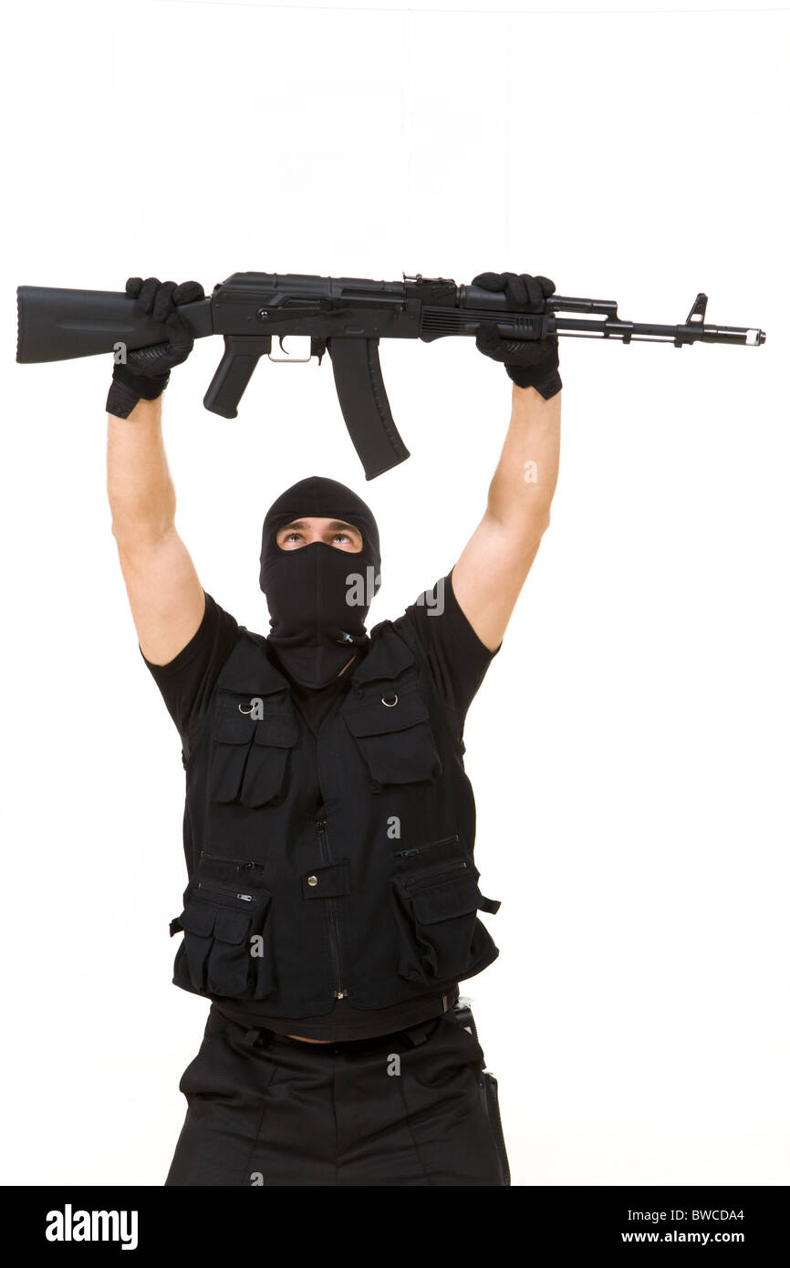 Portrait of terrorist in balaclava holding rifle above himself on white background Stock Photo