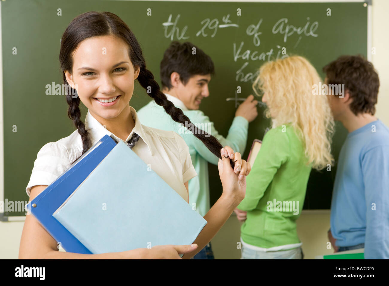 Portrait of cute girl holding textbook in hands on background of ...
