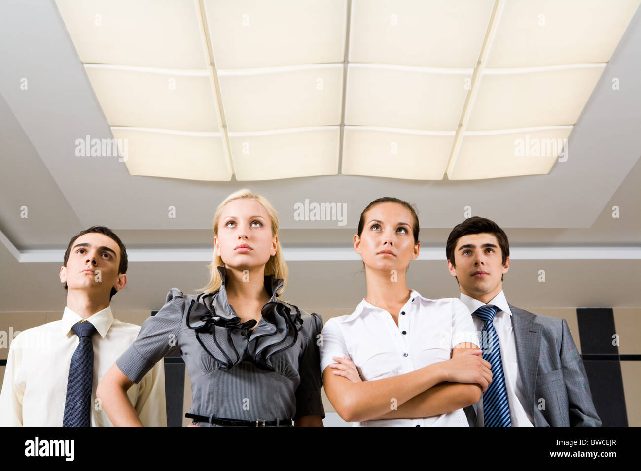 Several confident employees standing in row and looking upwards seriously Stock Photo