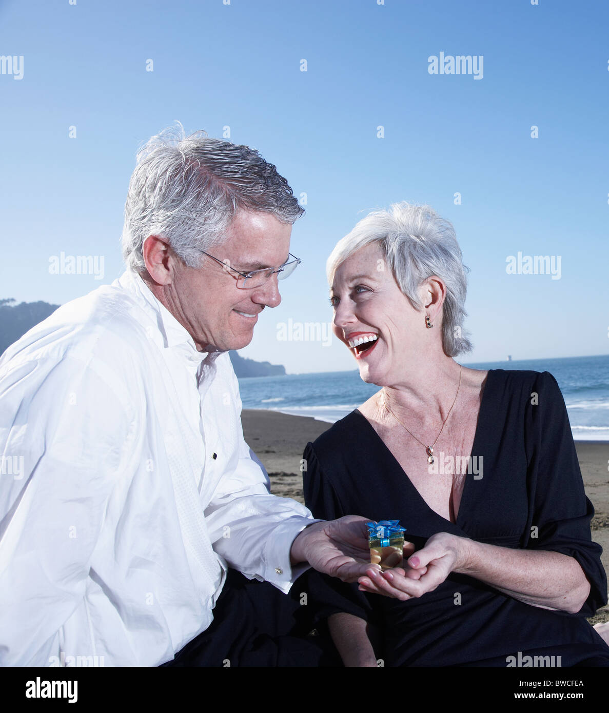 USA, California, Fairfax, Happy mature mag giving small gift to woman on beach Stock Photo