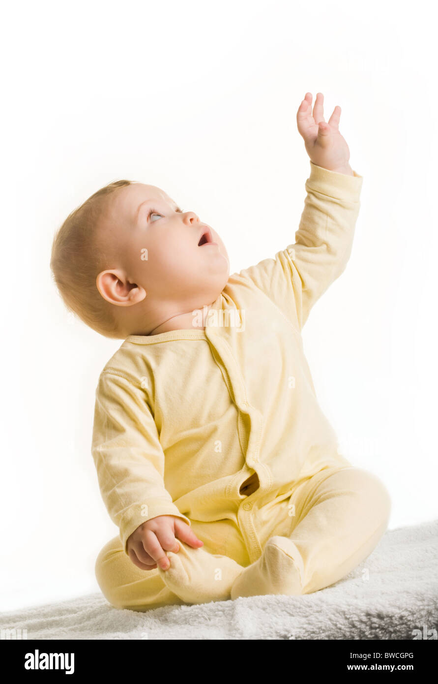 Portrait of adorable baby sitting with his arm raised and looking