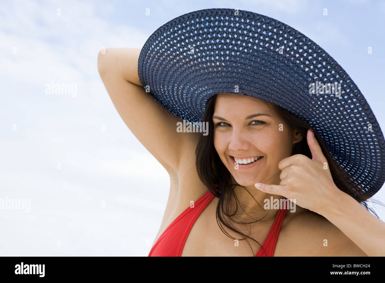 Portrait of pretty young lady in hat making gesture by her face and smiling Stock Photo