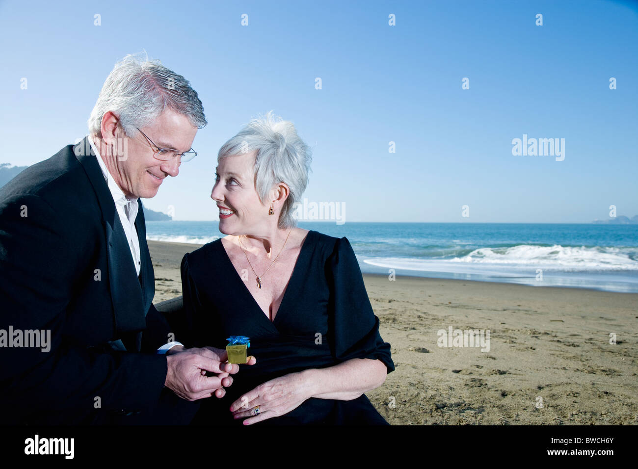 USA, California, Fairfax, Happy mature mag giving small gift to woman on beach Stock Photo