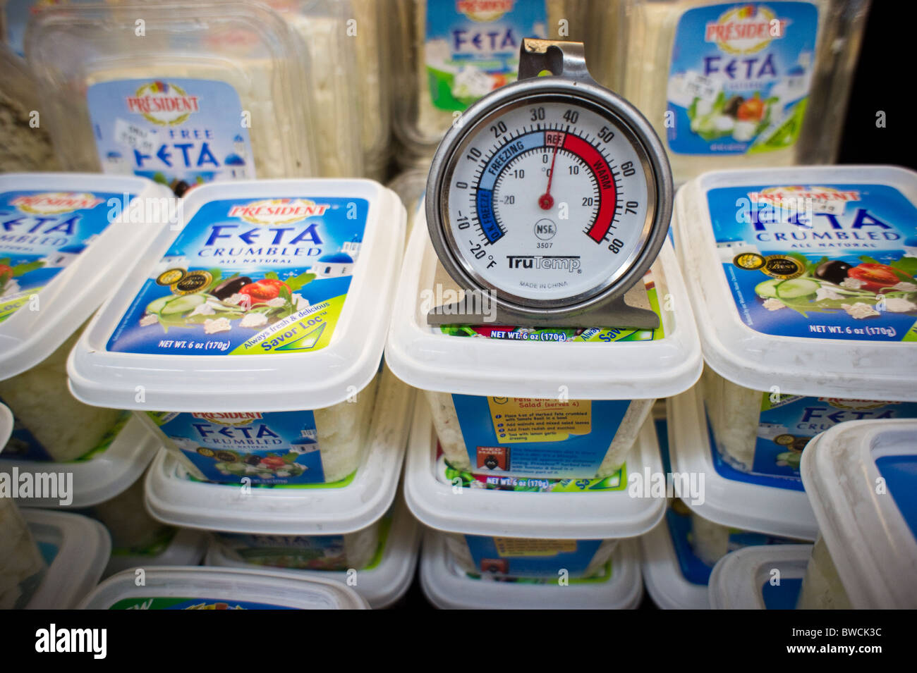 A thermometer measures the temperature of a dairy case containing feta