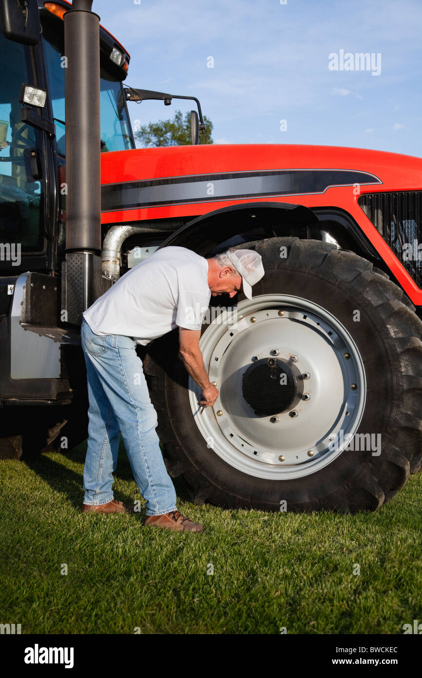 USA, Illinois, Metamora, Farmer repairing tractor wheel Stock Photo