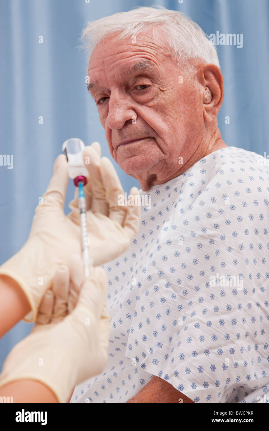 USA, Illinois, Metamora, Senior man looking at doctor's hands holding syringe Stock Photo