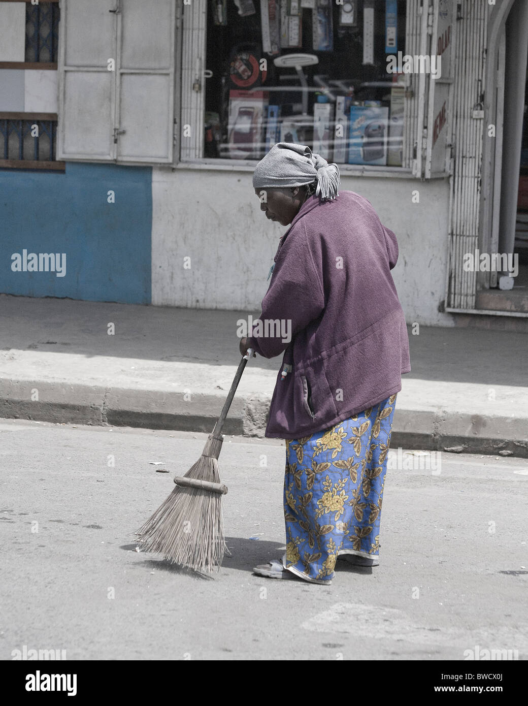 An old African woman sweeps the street in Arusha, Tanzania. Stock Photo