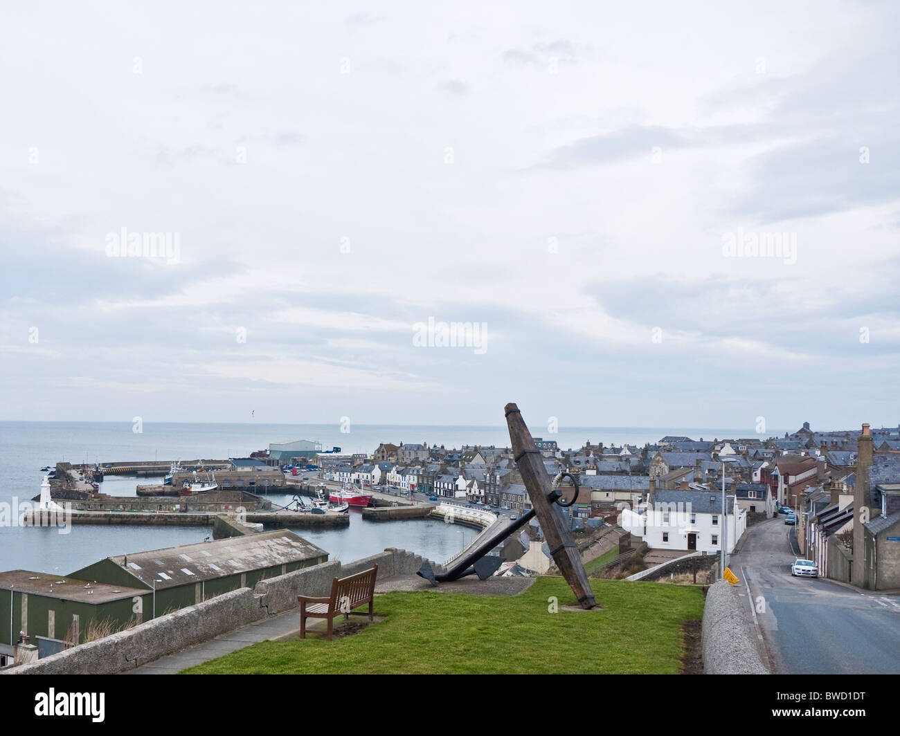 View over Maduff harbour from Church Street with bench and large anchor in the foreground, Macduff, Aberdeenshire, Scotland, UK Stock Photo