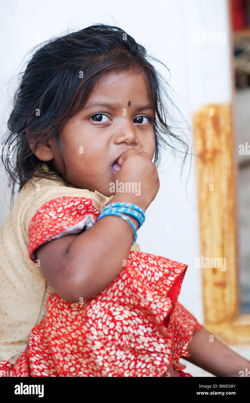 Small Indian rural village girl eats rags ball for breakfast, in the doorway of her home.  Andhra Pradesh, India Stock Photo