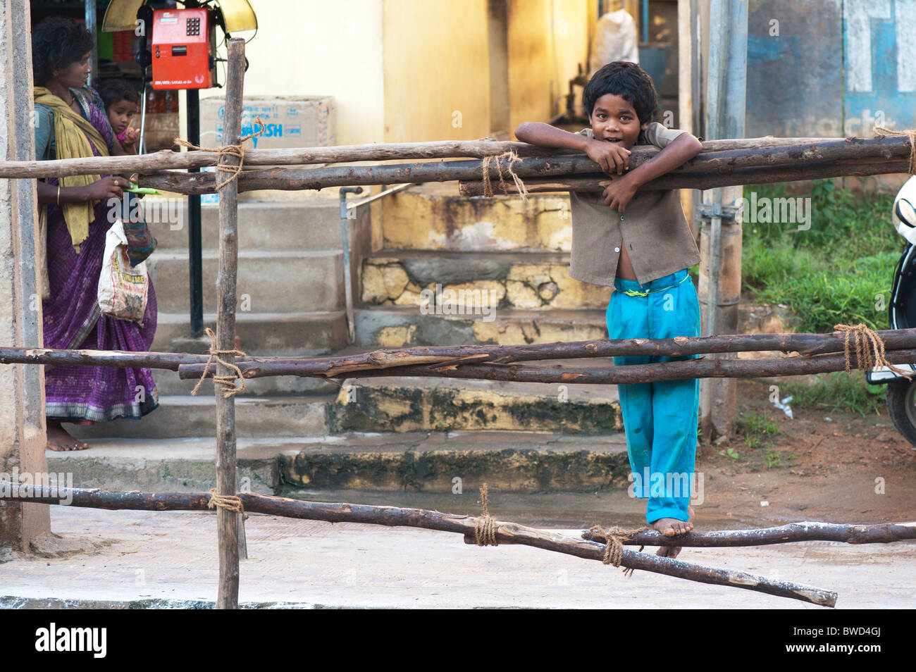 Happy young Indian street boy smiling standing on a wooden fence in the town of Puttaparhi, Andhra Pradesh, India Stock Photo