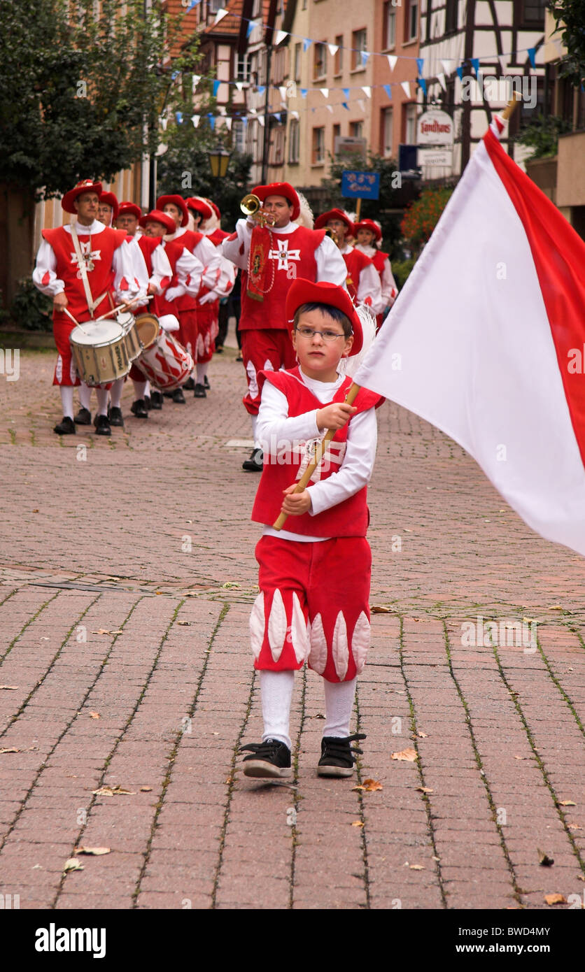 Young boy, standard bearer, musicians in costume, street parade