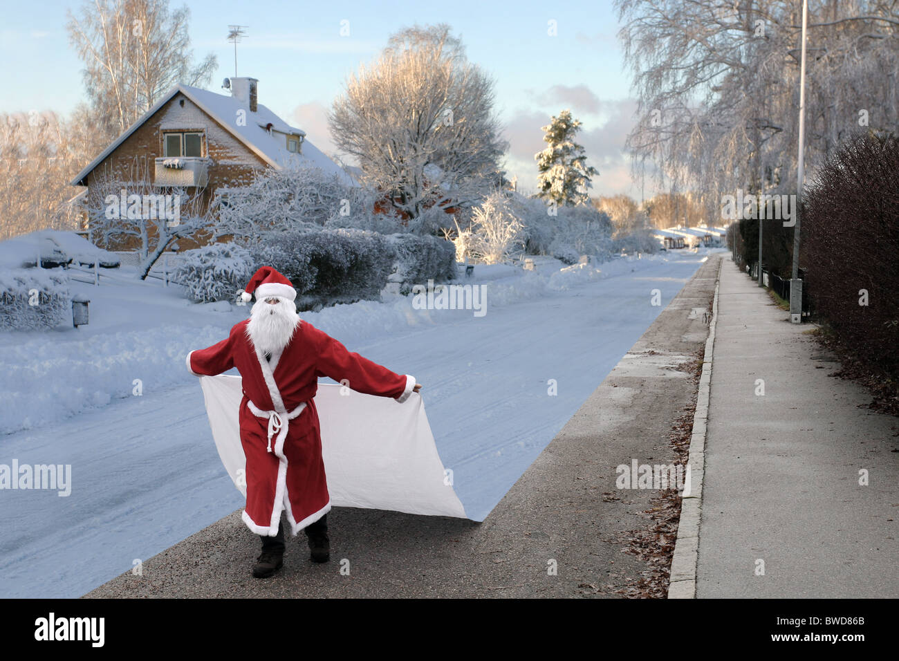 Santa Claus changing the season to winter by laying a sheet of snow on the ground. Stock Photo