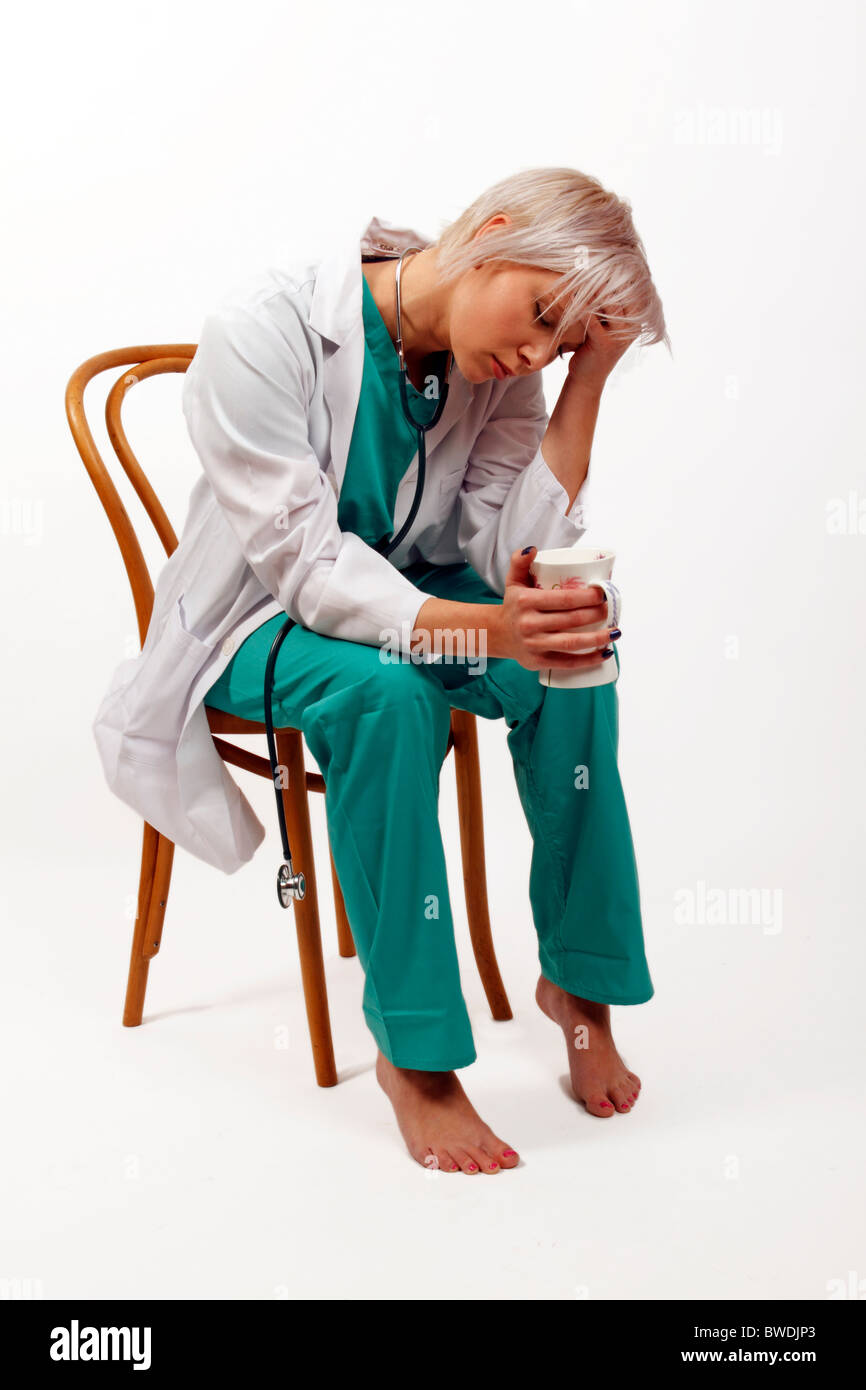 young doctor after a long shift looking exhausted drinking coffee Stock Photo