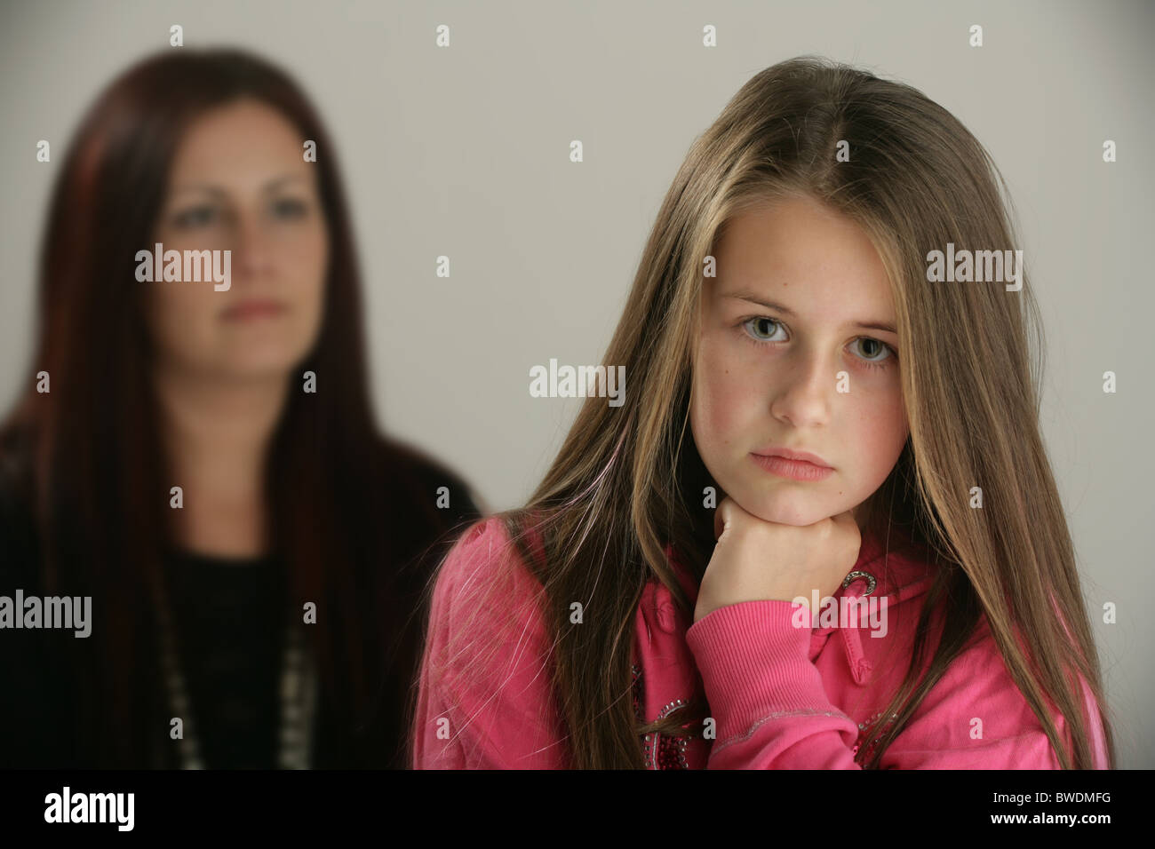 A sad ten year old girl with her mother in the background. Stock Photo
