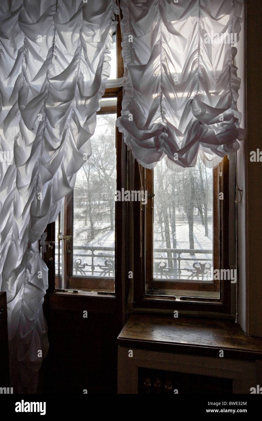 'Russian interior' view through ruched curtains and wrought iron railings on to snowy park Stock Photo