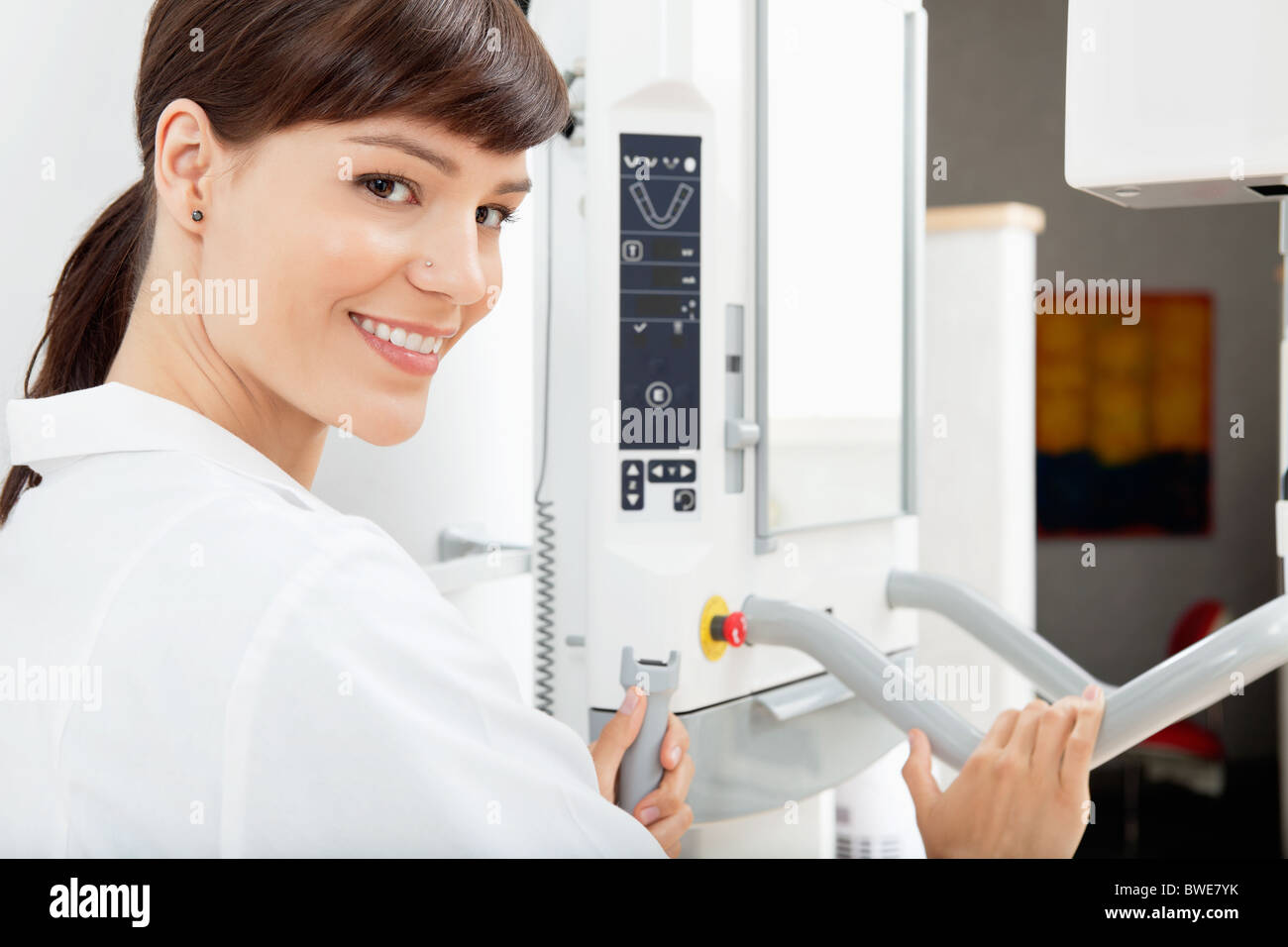 Portrait of a happy female dentist with a Panoramic Imager X-Ray machine Stock Photo