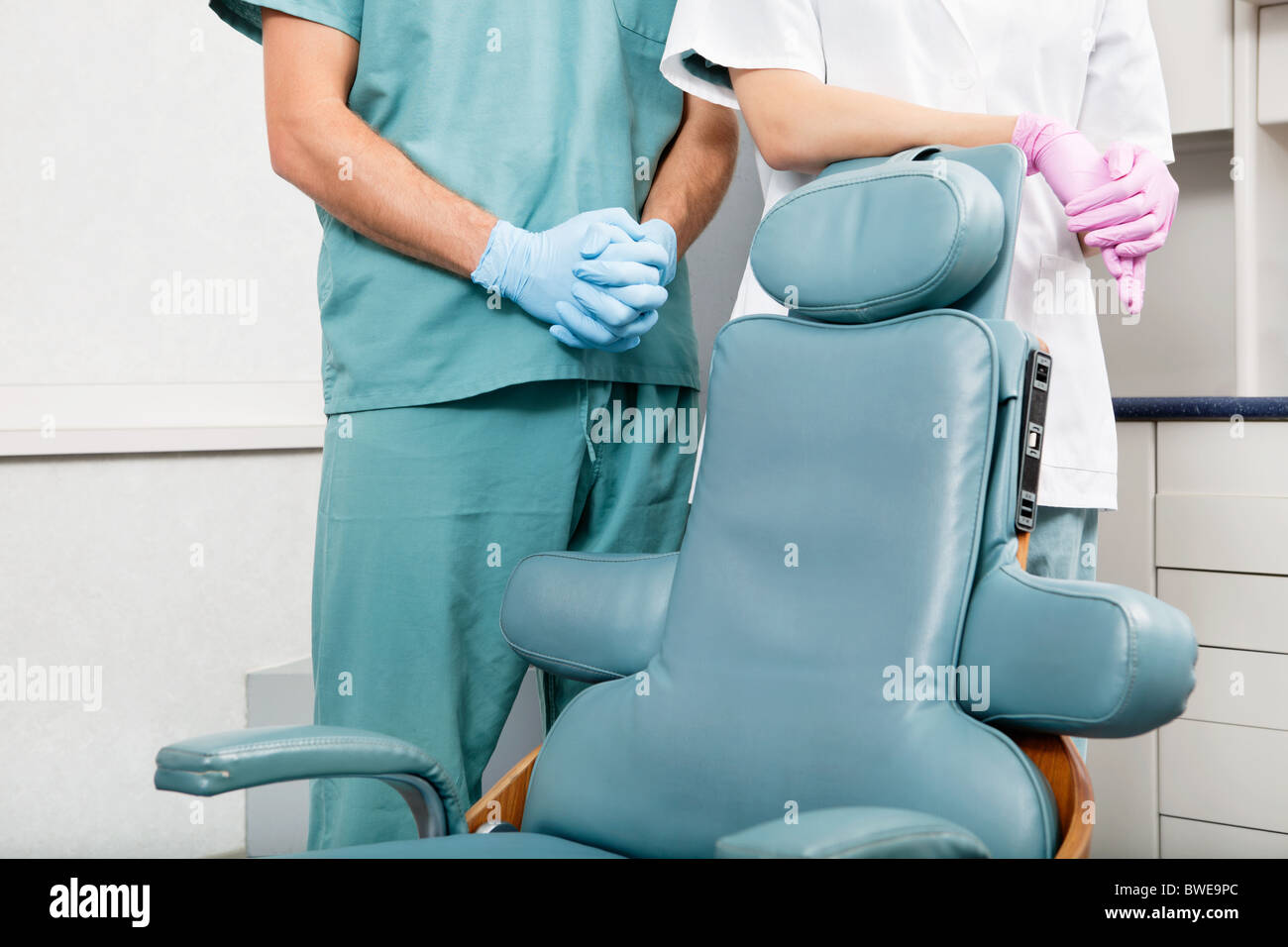 Midsection of a dentist and female assistant in exam room by dentist's chair Stock Photo