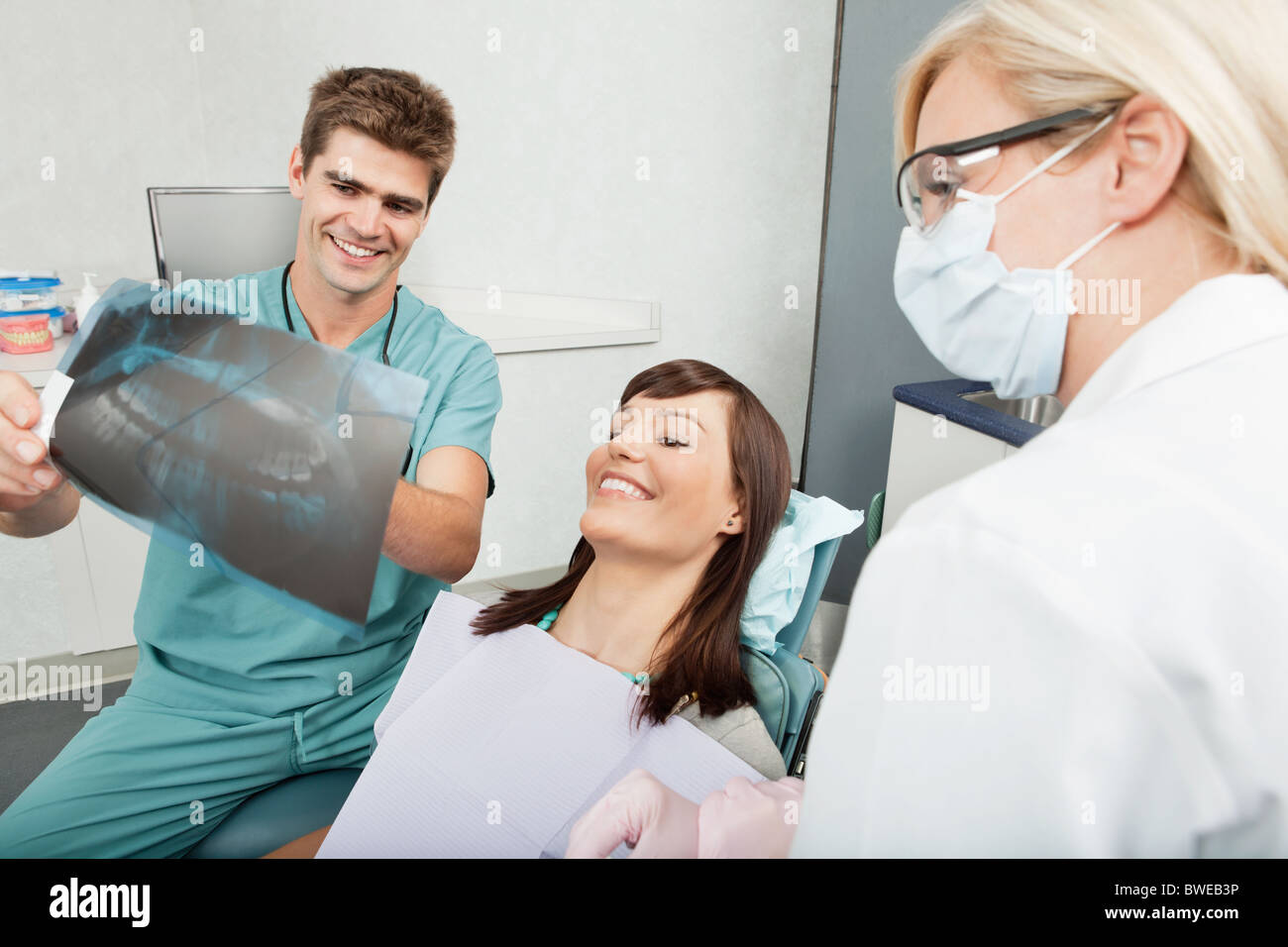 Smiling male dentist explaining the details of x-ray to a beautiful female patient Stock Photo