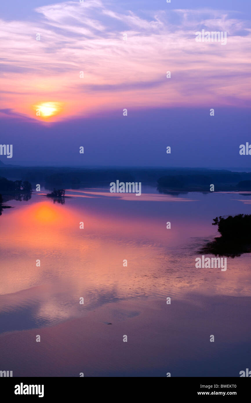 The sun sets through a layer of clouds over the Mississippi River near Savanna, IL. Stock Photo
