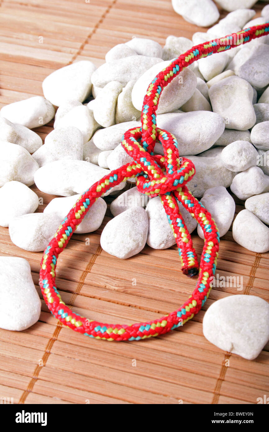 A fine knotted bowline knot lying on a pile of rocks Stock Photo - Alamy