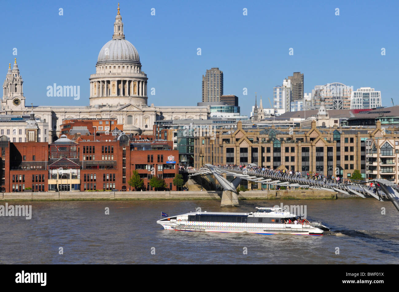 River Thames clipper boat with no advertising passing St Pauls Cathedral and the Millennium Bridge Stock Photo