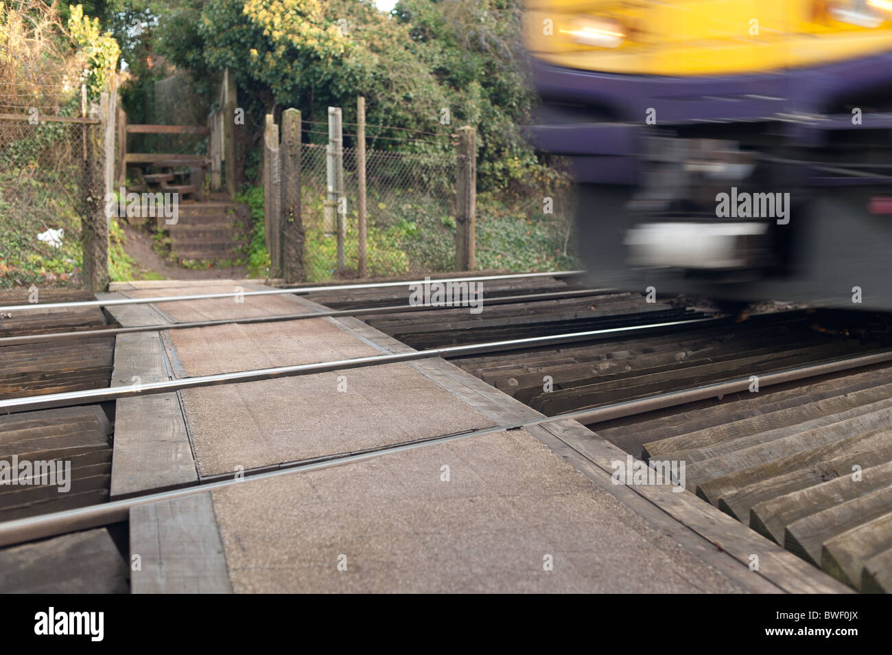 Unmanned pedestrian railway crossing footpath warning signs and passing train South eastern Trains Stock Photo