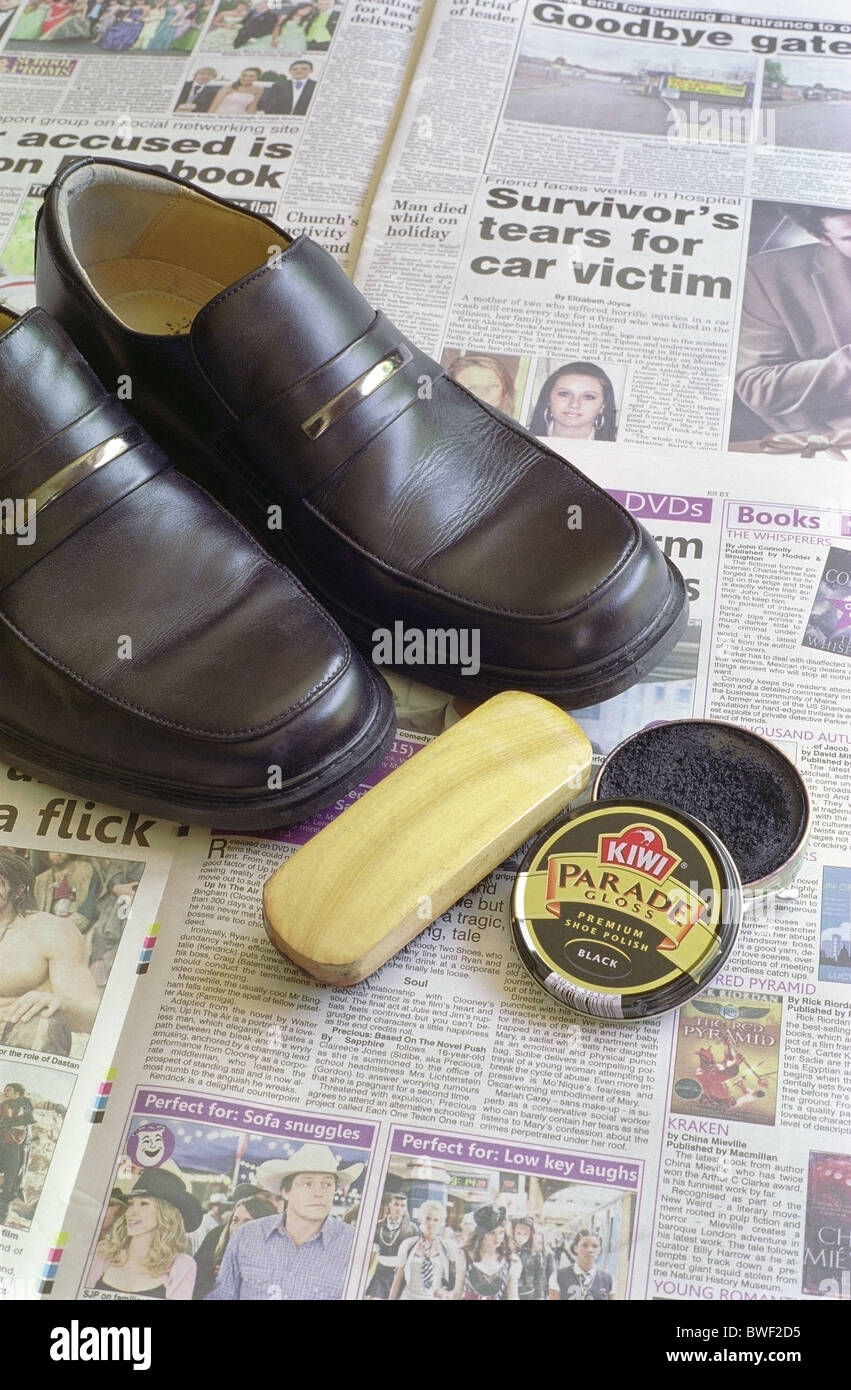 Pair of Clarks Brand Mens Black Leather Shoes on newspaper with Kiwi Brand Shoe Polish and Brush Stock Photo