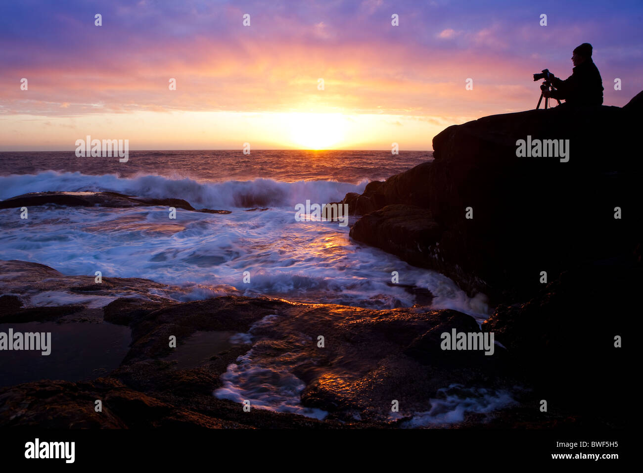 A photograper taking photos of the sunset on the Island Runde,Norway Stock Photo